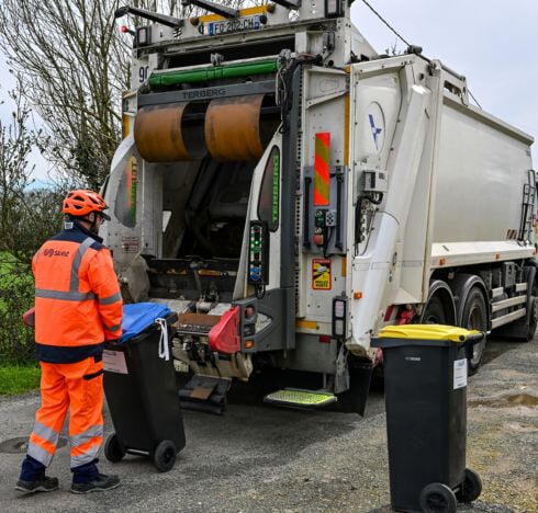 Un éboueur amène une poubelle au camion
